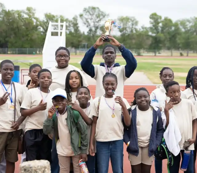 The children's camp team lifting their trophy on the track