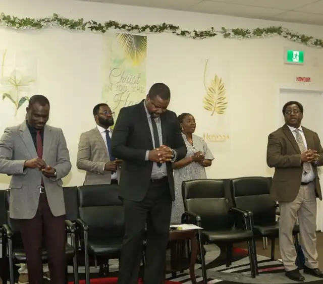 Church leaders standing together in prayer at the front of the hall